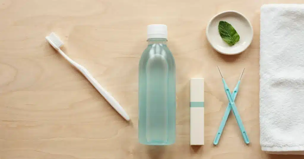 Gum Disease 101: Signs, Stages, Causes, and How to Treat It Flat lay of toothbrush, floss, and mouthwash used to treat and prevent gum disease